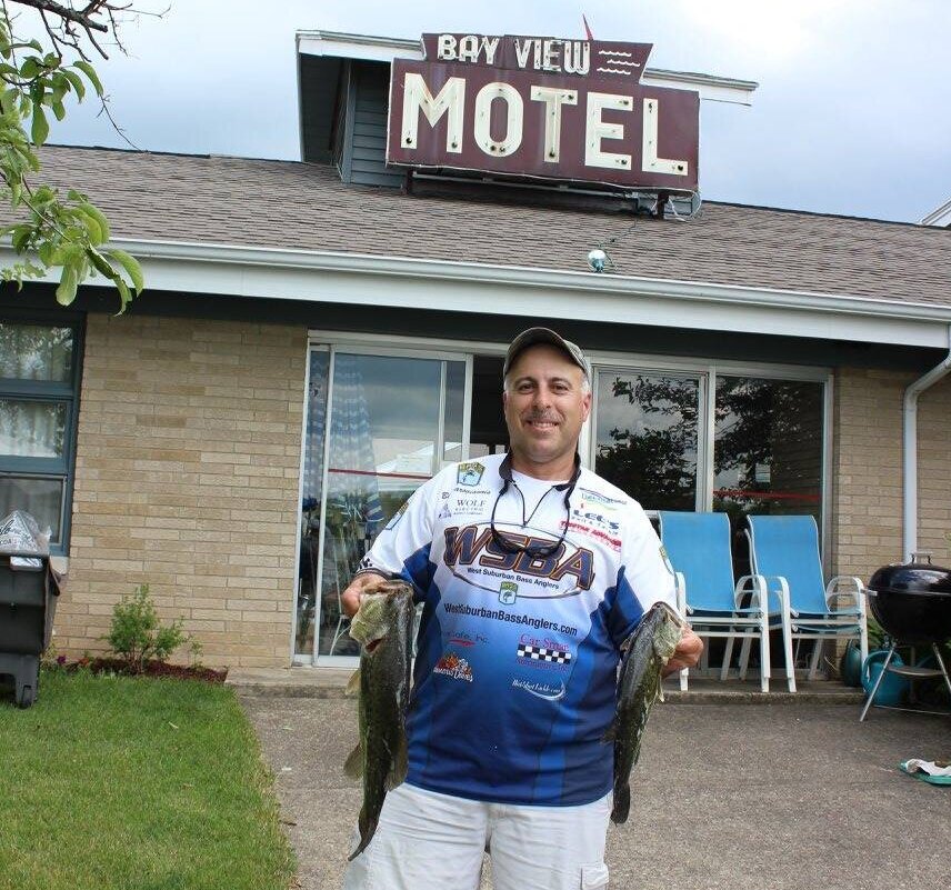 guy holding fish in front of motel